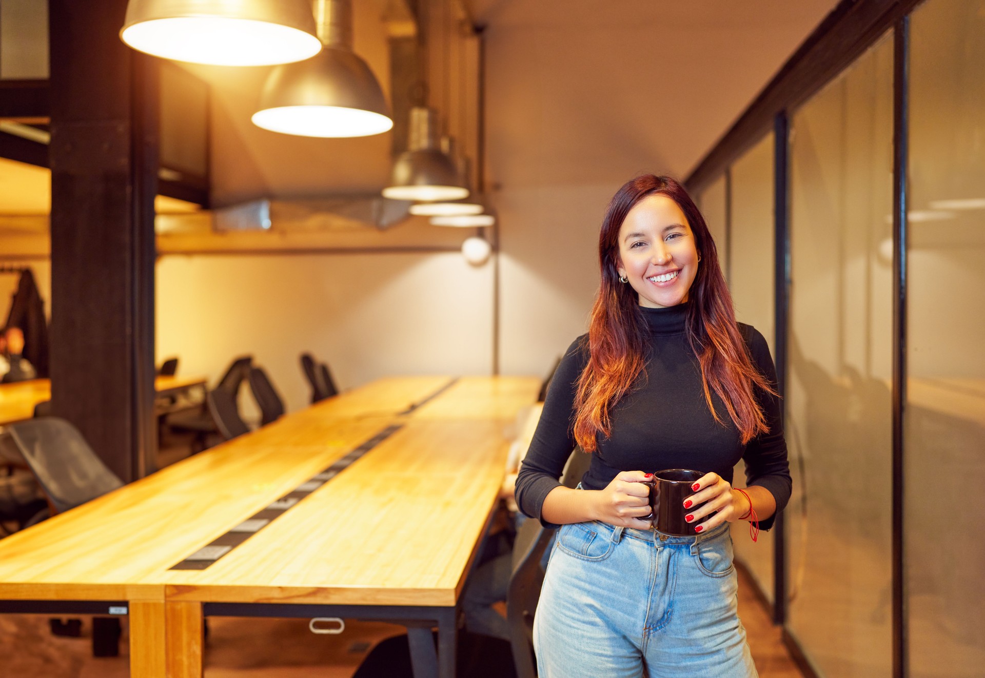 portrait beautiful young latin american woman in coworking office with a cup of coffee
