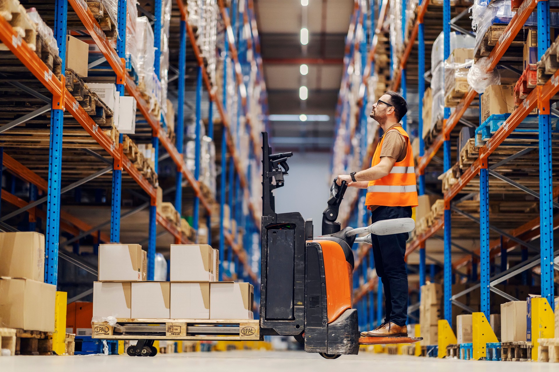 A forklift driver is collecting and organizing boxes with goods in storage.