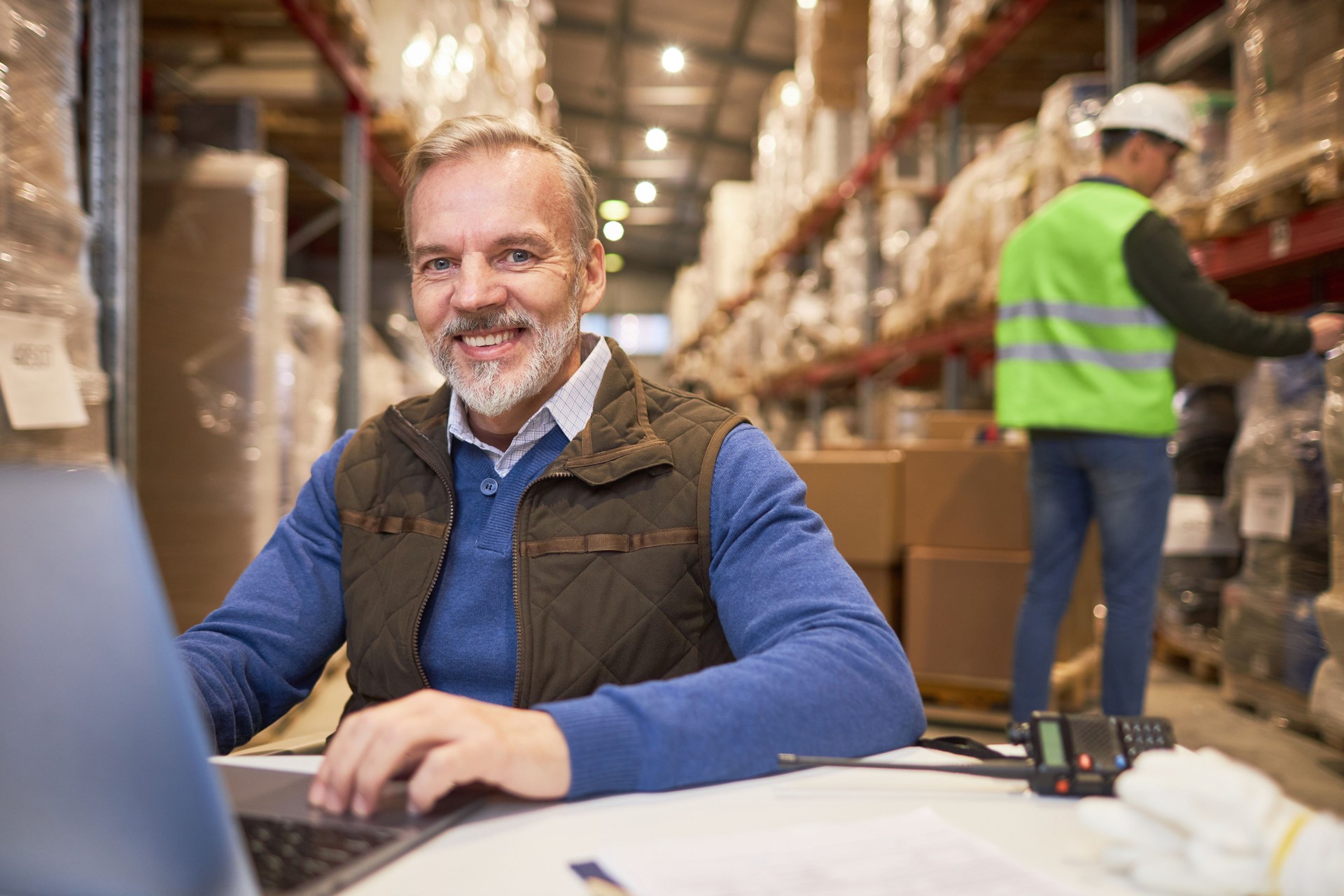 Smiling senior man using laptop in warehouse